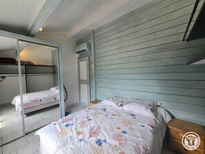 A room with two bunk beds, a mirrored closet, and a bed with a floral bedspread. - Private chalet, pool and AC near Castelnaud - 4 guests (Castelnaud-la-Chapelle)