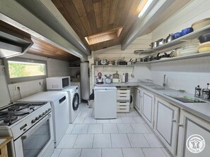 A compact kitchen with a stove, microwave, washing machine, and a small refrigerator. - Private chalet, pool and AC near Castelnaud - 4 guests (Castelnaud-la-Chapelle)