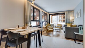 Una sala moderna con comedor, ventanas amplias y vistas a un paisaje nevado.
