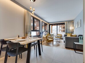 A modern living room with a dining area, large windows, and a view of a snowy landscape. - Modern apt with Spa and parking, Arc 1800 (Les Arcs 1800)