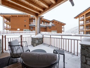 A covered outdoor seating area with stone pillars, wooden beams, and a view of a multi-story building with balconies. - Modern apt with Spa and parking, Arc 1800 (Les Arcs 1800)