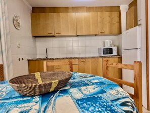 Una cocina compacta con armarios de madera, un microondas y un refrigerador.