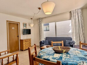 Ein Zimmer mit einem hölzernen Bett, einem an der Wand befestigten Fernseher, einer Holzkommode und einem Fenster mit Vorhängen.