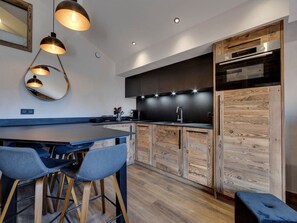 A modern kitchen with a central island, bar stools, and wooden cabinetry. - Renovated apartment in Val-d'Isère - 4 guests (Val-d'Isère)