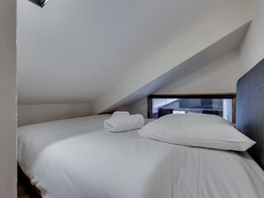 A single bed in a room with a sloped ceiling, white bedding, and a visible window. - Renovated apartment in Val-d'Isère - 4 guests (Val-d'Isère)