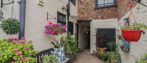 A narrow alleyway with hanging flower baskets and potted plants.