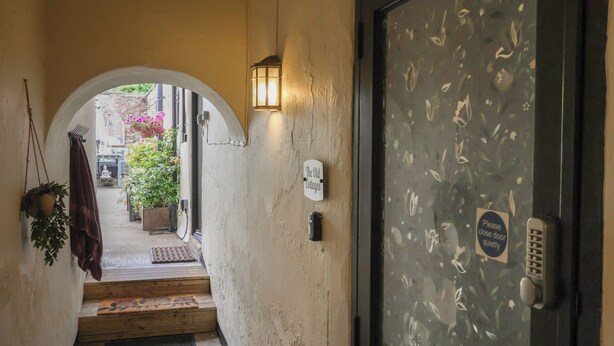A hallway with a wooden door, a sign reading 'The Old Cottages,' and a small window with a floral pattern. - No 1 Old Cottages (Ripon)