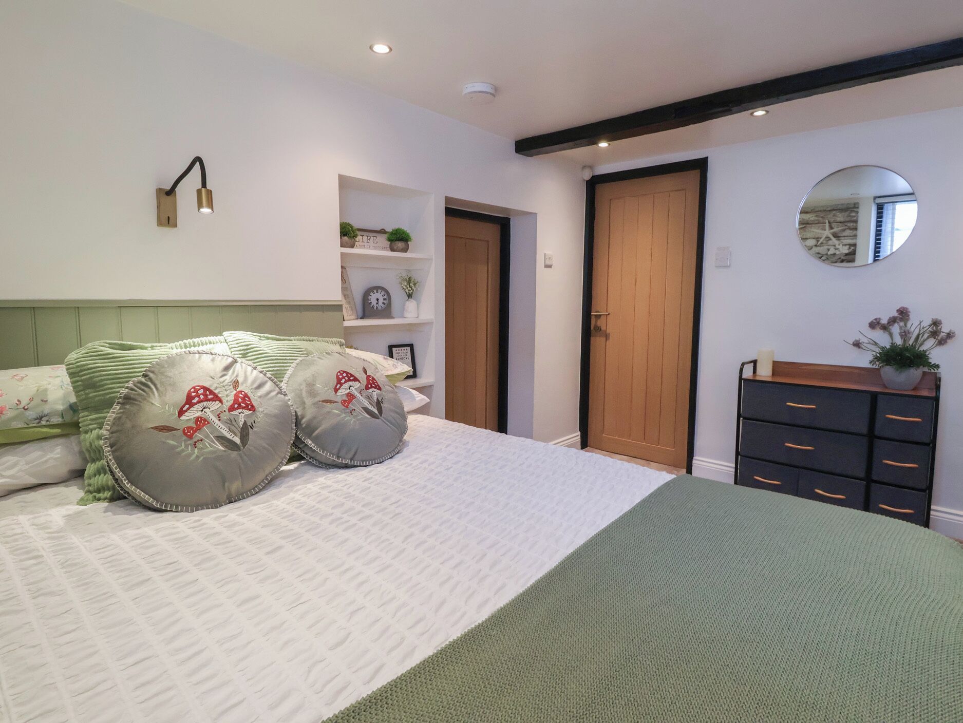 Une chambre à coucher avec un lit, une commode, un miroir et une porte.