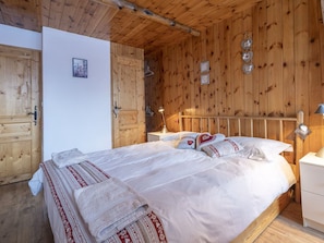 A wooden-paneled room with a bed, a bedside table, and a hanging light fixture. - Family apartment in center, mountain view - 4 guests (Val-d'Isère)