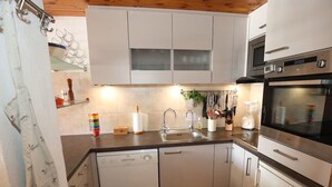 A kitchen with white cabinets, a dishwasher, a sink, and a stove. - Family apartment in center, mountain view - 4 guests (Val-d'Isère)