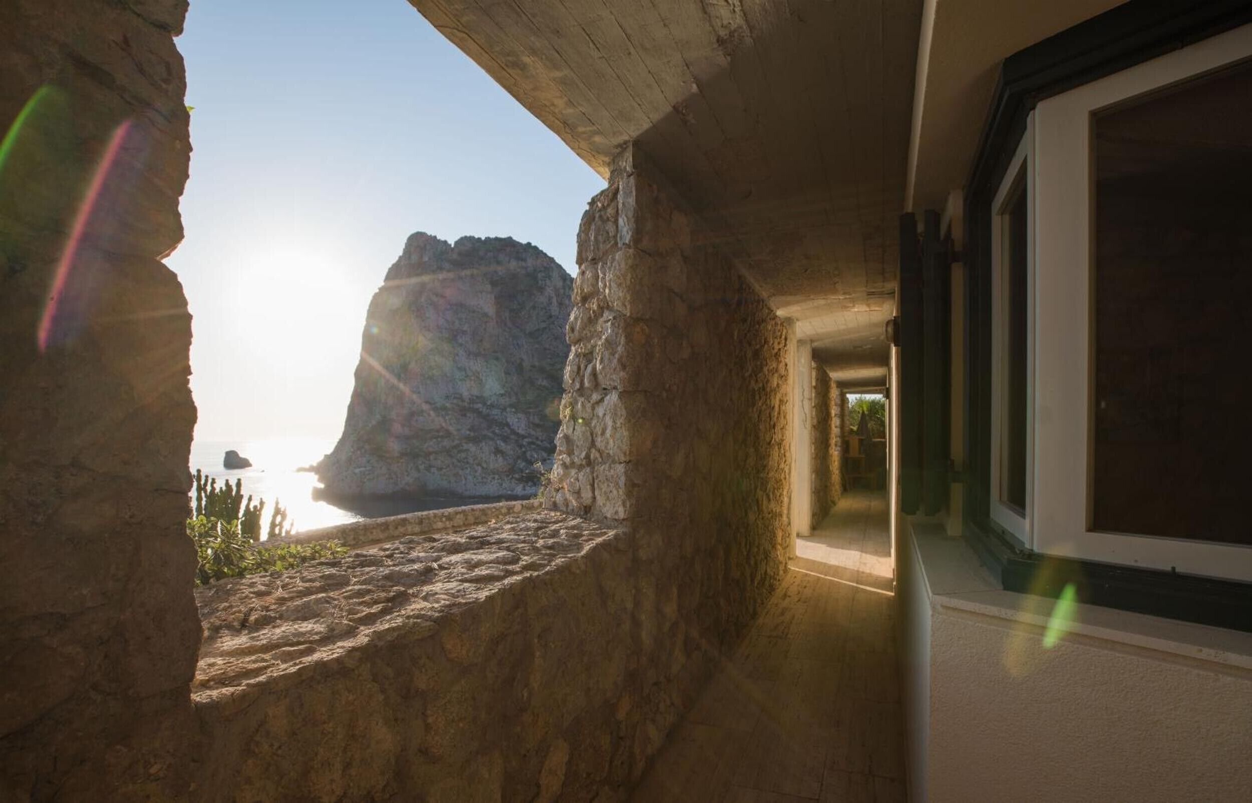 A stone interior with a view of the sea through a window.