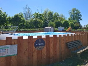 Uima-altaan ympärillä on puinen aita, ja siinä on kyltti, jossa lukee: ”PISCINE”.