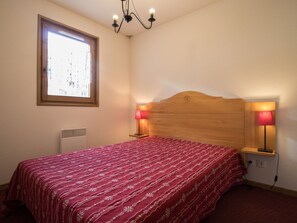 Ein Schlafzimmer mit Holzkopfende, zwei Nachttischlampen, einem Fenster und einer Heizung.