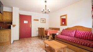 A compact living space with a kitchenette, a dining area, and a sofa. - Spacious apartment, parking - 6 guests (Lanslevillard)
