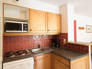 A kitchen with wooden cabinets, a microwave, a stove, and a coffee maker. - Spacious apartment, parking - 6 guests (Lanslevillard)