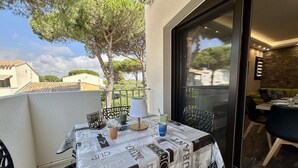 Un balcon avec une table dressée pour deux personnes, une chaise et une vue sur les environs.