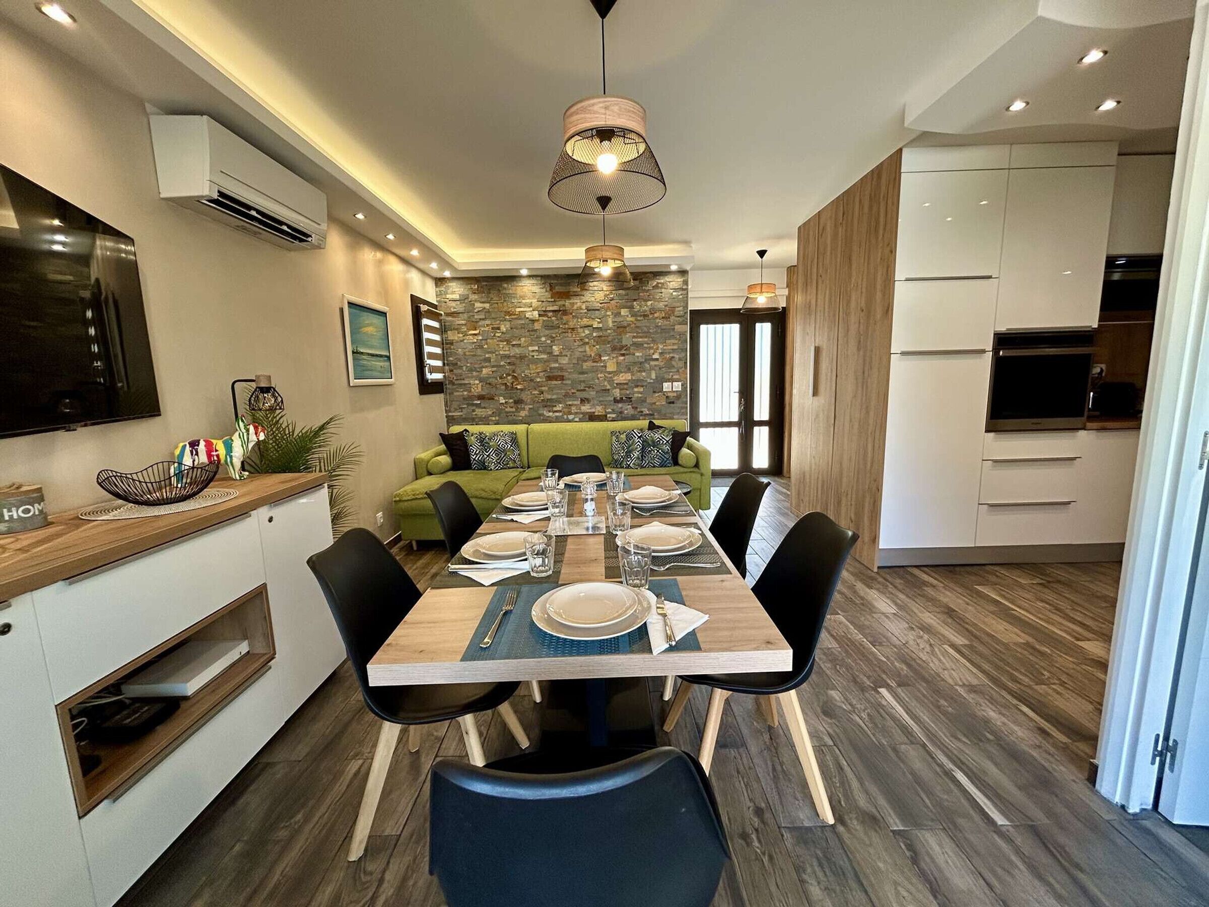 A modern kitchen with white cabinets, a built-in oven, and a large TV.