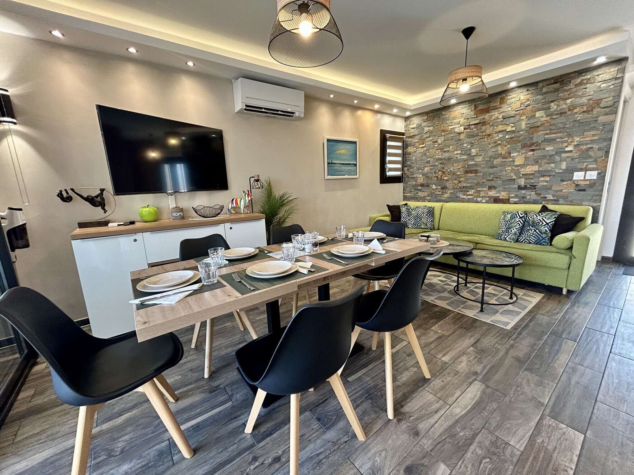Un comedor moderno con una mesa de madera, sillas negras y un sofá verde.