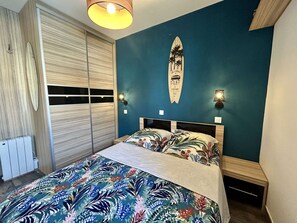 Ein Schlafzimmer mit einem Bett, einer Surfbrett-Dekoration und einem Fenster mit Jalousien.