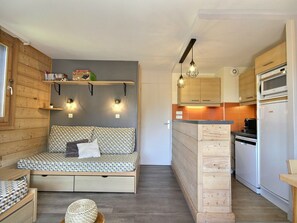 A compact room with a built-in sofa bed, a kitchenette with a microwave and oven, and a small dining area. - Apartment with station view - 4 guests (La Plagne 1800)