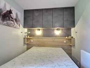 Een slaapkamer met een bed, een houten hoofdbord, wandplanken en een beren schilderij.