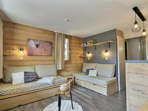 Ein gemütlicher Raum im Chalet-Stil mit zwei gemusterten Sofas, einem kleinen runden Tisch und einer Holzkabine.