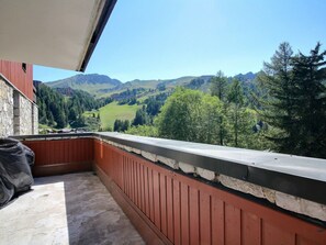 Ein Balkon mit Steinmauer und Blick auf eine gebirgige Landschaft.