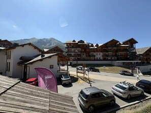 A hotel with multiple wooden buildings, a parking area, and a mountain backdrop. - Ski-in/ski-out apartment - 8 guests (Les Orres)