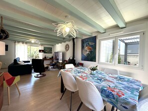 Un coin repas avec une table dressée pour quatre personnes, entourée de chaises blanches.