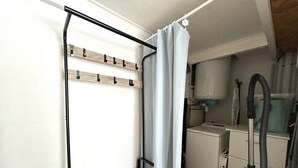 Eine kleine Küchenzeile mit integriertem Waschmaschine, Staubsauger und einem Holzbodenregal.