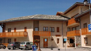 A multi-story building with balconies, a parking sign, and a directional sign indicating a nearby location. - Comfortable apartment for 6 with terrace in Aussois (Aussois)