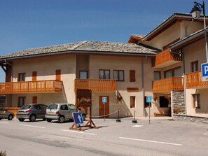 A multi-story building with balconies, a parking sign, and a directional sign indicating a nearby location. - Comfortable apartment for 6 with terrace in Aussois (Aussois)