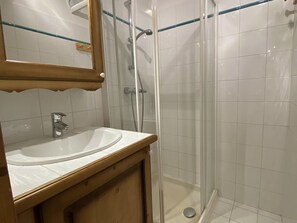A bathroom with a sink, mirror, and glass-enclosed shower. - Apartment with pool - 4 guests (Crest-Voland)