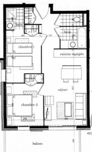 Un plan d’étage comprenant deux chambres, une cuisine, une salle de bain, un salon et un balcon.