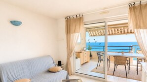A room with a sofa, a small table, and a view of the sea through a glass door. - Air-conditioned apartment, sea view - 4/6 guests (Sète)