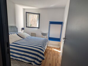 Une chambre à coucher avec un lit, une fenêtre, une chaise et une porte.