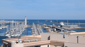 A marina with numerous boats docked, a lighthouse, and a clear blue sky. - Stunning T2 AC, sea view - 4 guests (Sète)