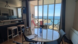 A modern kitchen with a view of the sea, a dining area with a table and chairs, and a balcony with a chair. - Stunning T2 AC, sea view - 4 guests (Sète)