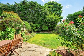 A garden with a stone bench, a wooden table, and a variety of plants and trees. - Birchwood House London (Greater London)