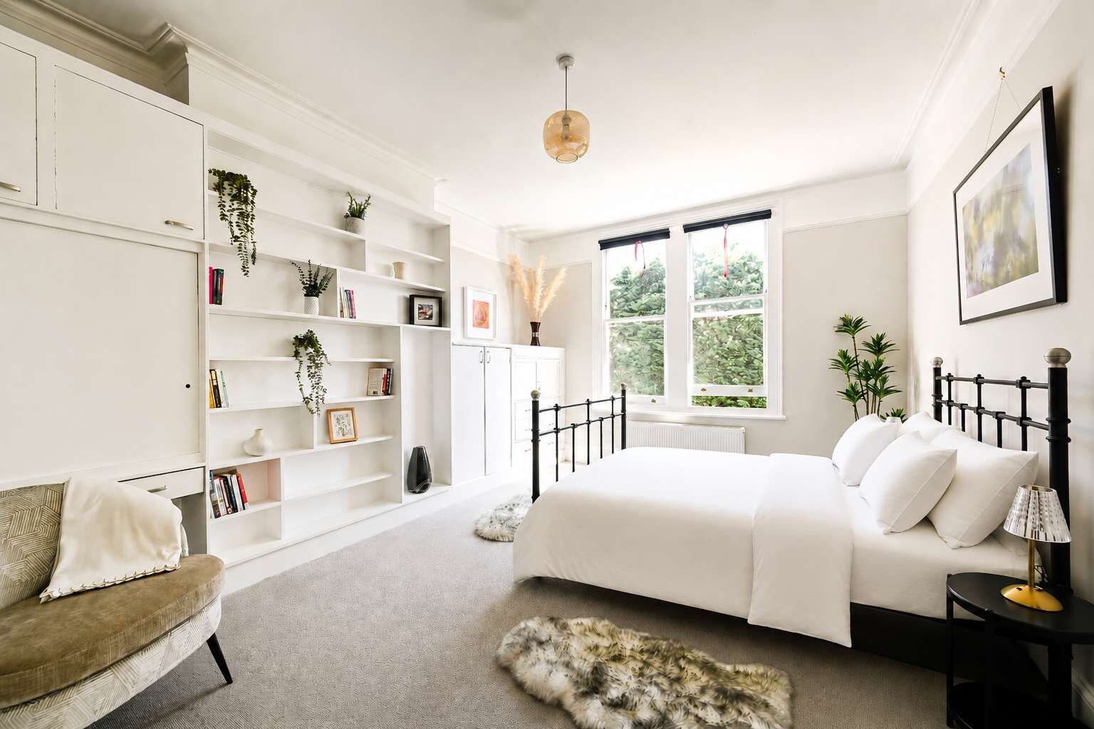 Ein Schlafzimmer mit Bett, Sofa, Bücherregal und Fenster.