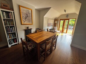 Ein Essbereich mit einem Holztisch und Stühlen, einem Bücherregal und einem Bild an der Wand.