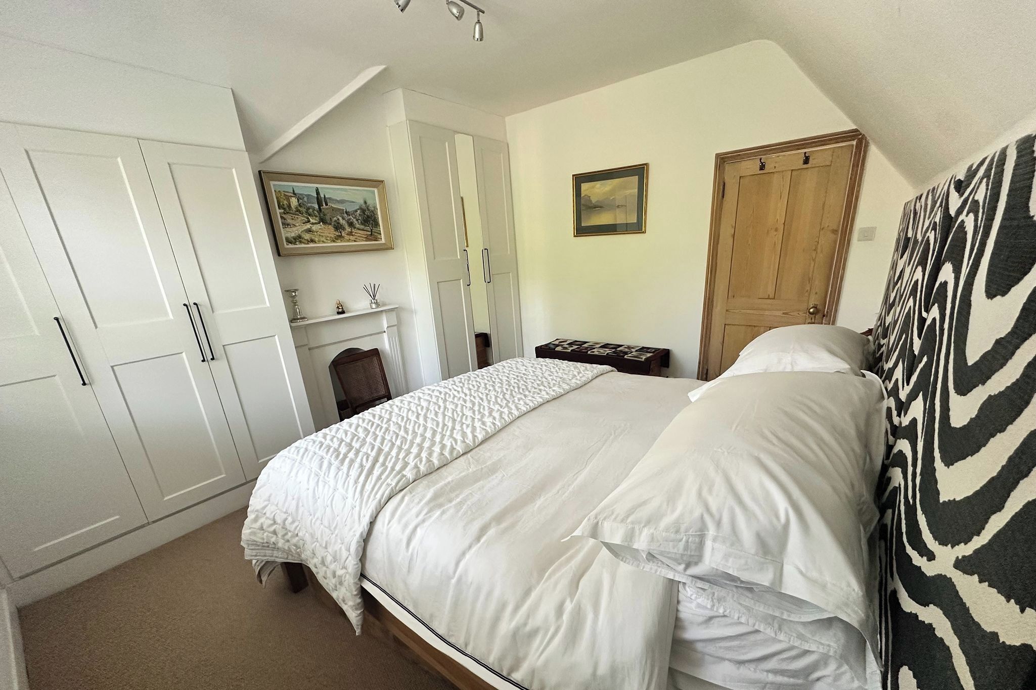Un dormitorio con cama, armario, chimenea y puerta.