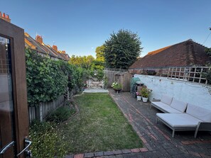 Ein Garten mit Rasen, einem Holzzaun, einer weißen Wand und einer weißen Bank.