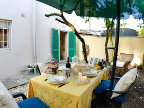 An outdoor dining area with a table set for two, a birdcage, and a wicker chair. - Angelina by Interhome (Lido di Camaiore)