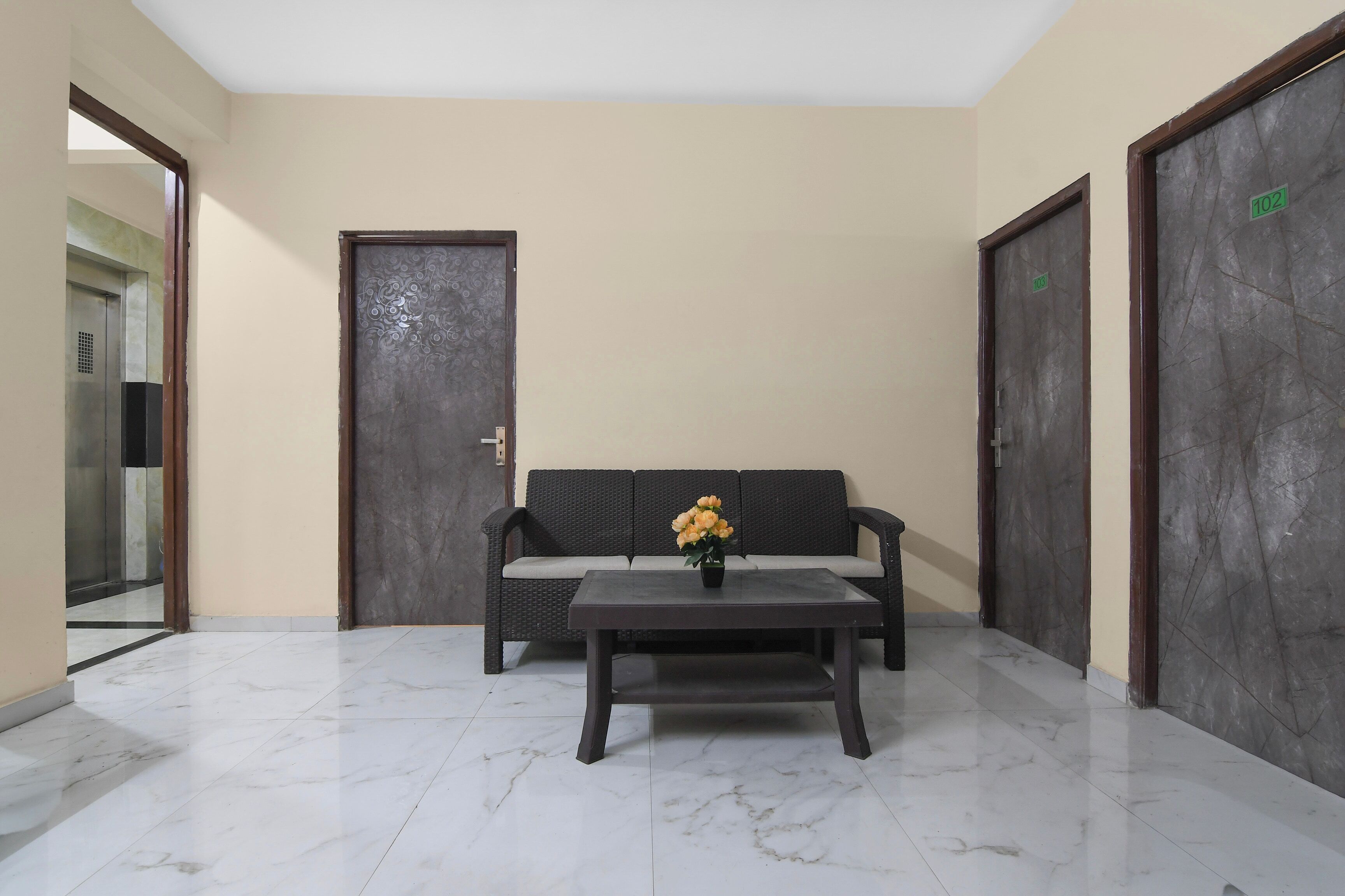 A lobby with a sofa, a coffee table, and two doors.