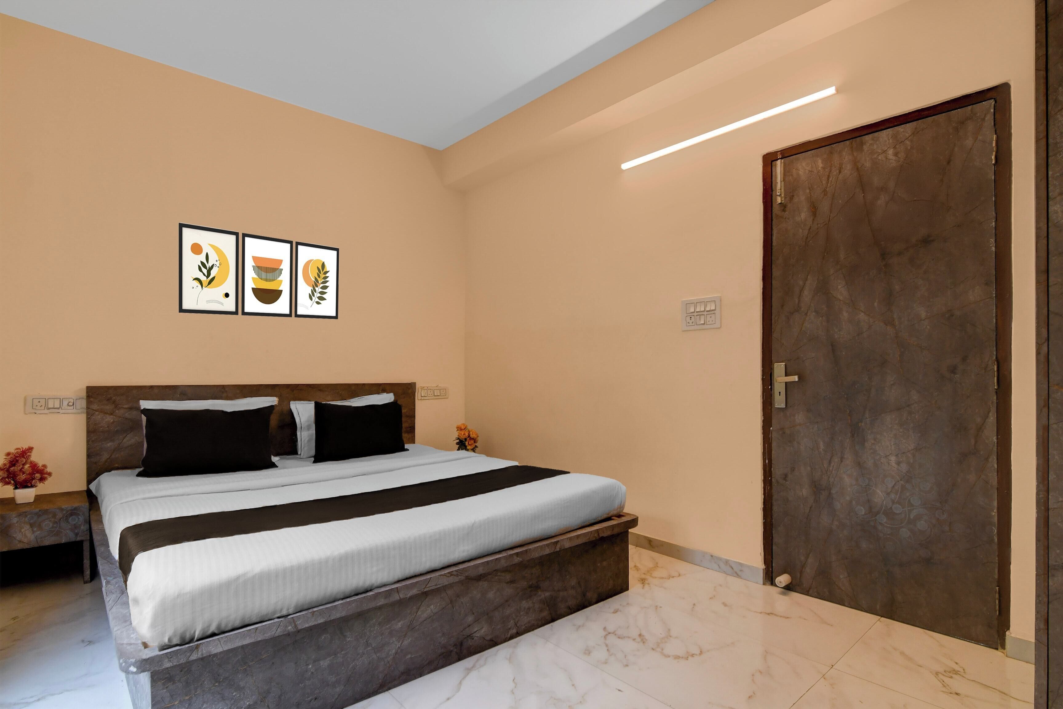 A bedroom with a bed, a nightstand, a wall-mounted light, and a door.