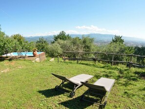 A grassy outdoor area with a pool, lounge chairs, and a view of distant mountains. - Bettina! by Interhome (Lucca)