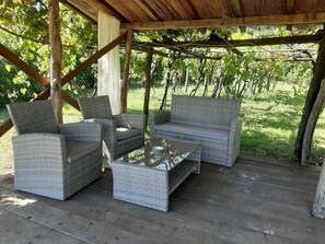 Uma área externa com assentos de vime e uma mesa de centro de vidro.