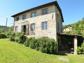 A stone house with a sloped roof, a covered porch, and a well-maintained garden. - Bettina! by Interhome (Lucca)