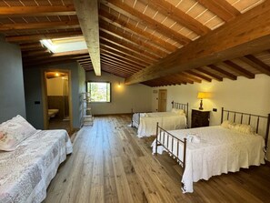 Een kamer met houten vloeren, een schuine plafond en twee bedden met witte lakens.